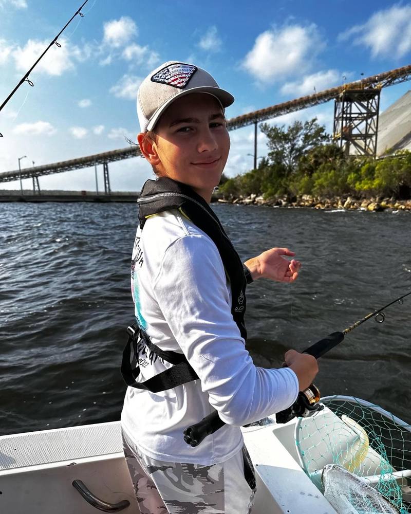 Camper fishing from a boat with the Jacksonville bridges behind