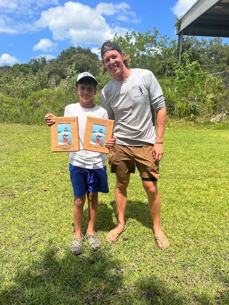 Camper holding two award plaques with Capt. Joe Carraway at the Friday awards