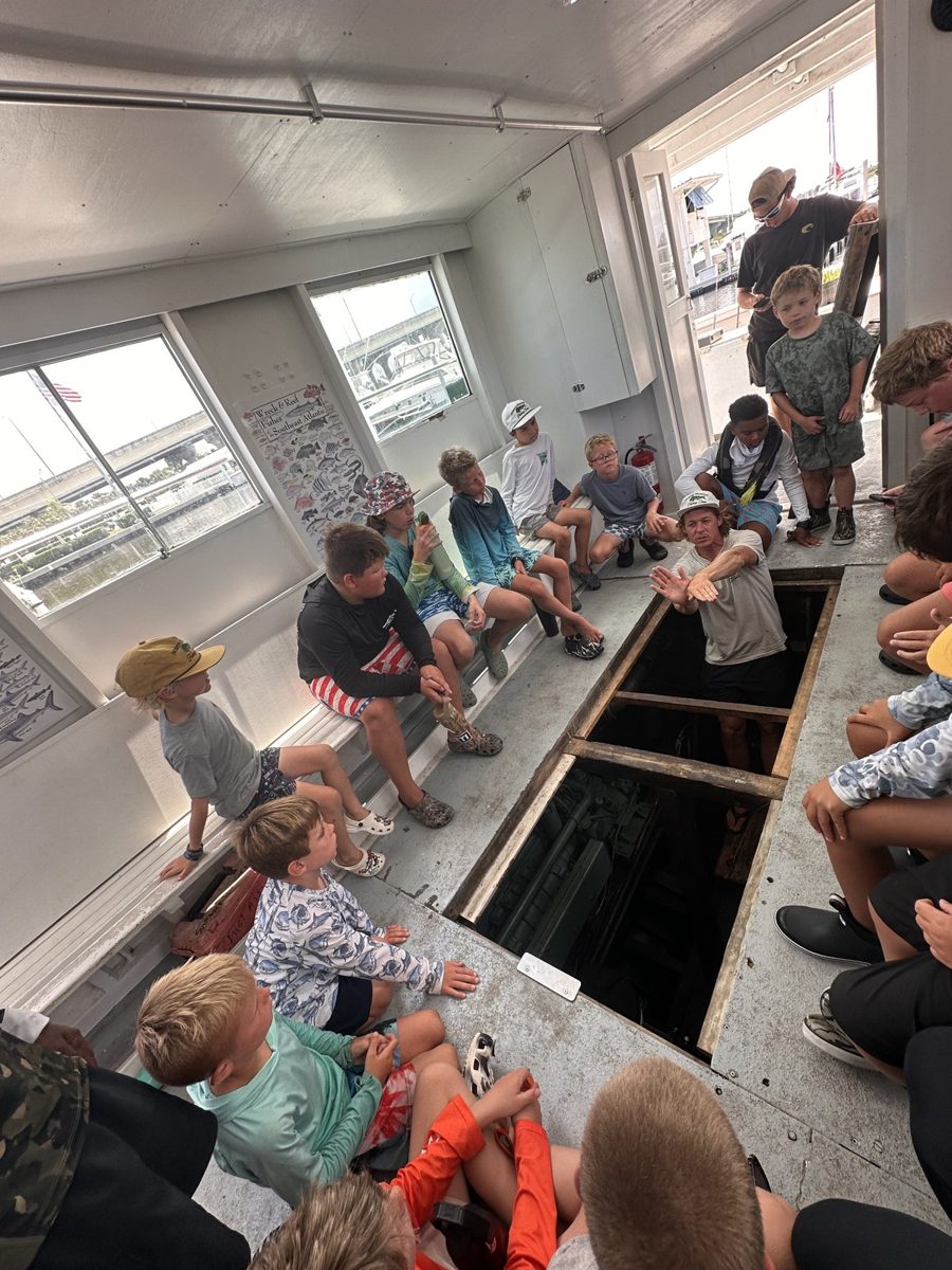 Campers looking down into the engine room of the head boat during a naval architecture lesson